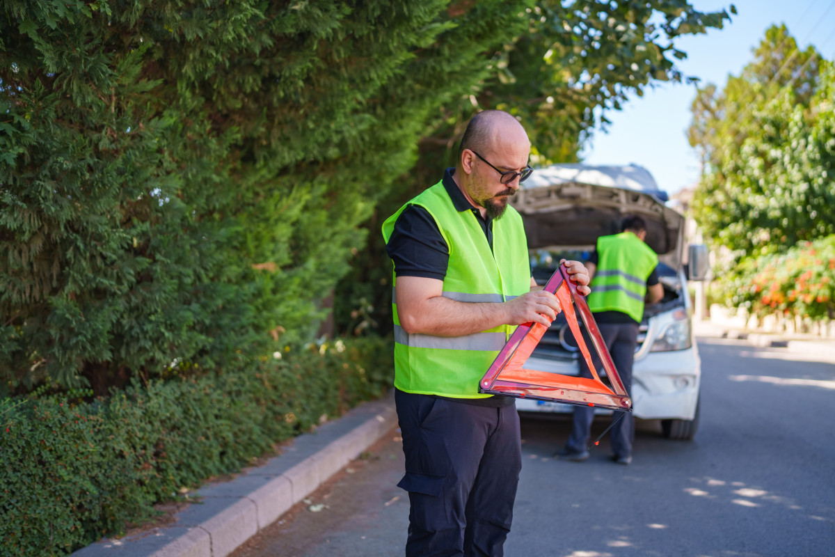 Mann stellt Warndreieck auf