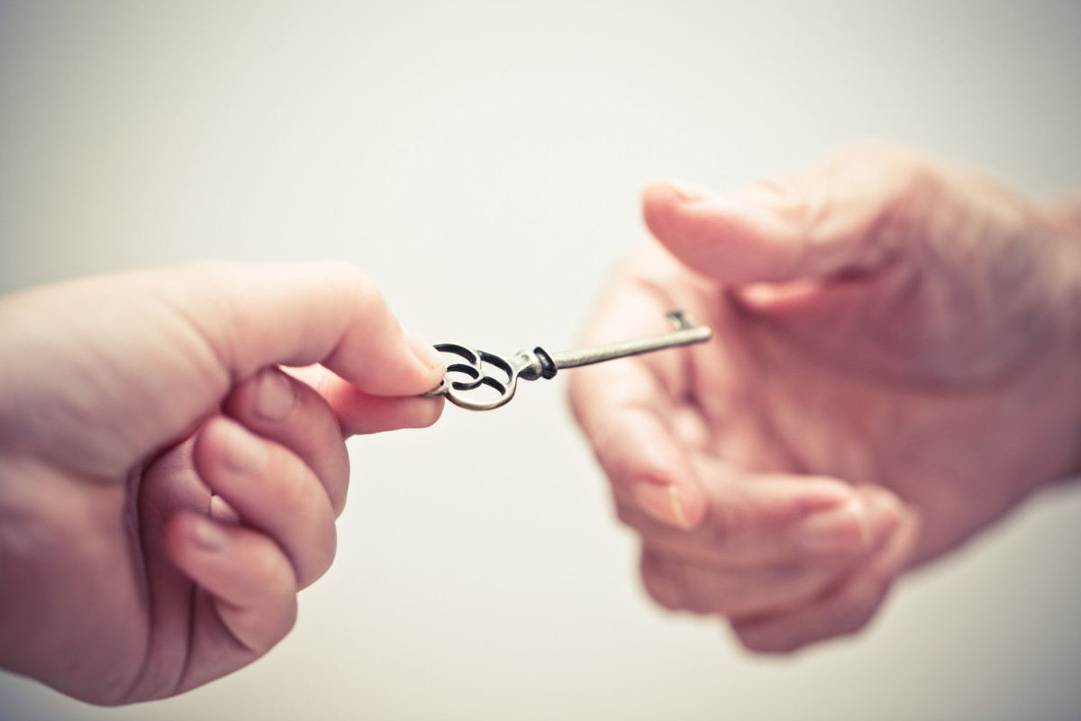 Zwei Hände übergeben eine Schlüssel.