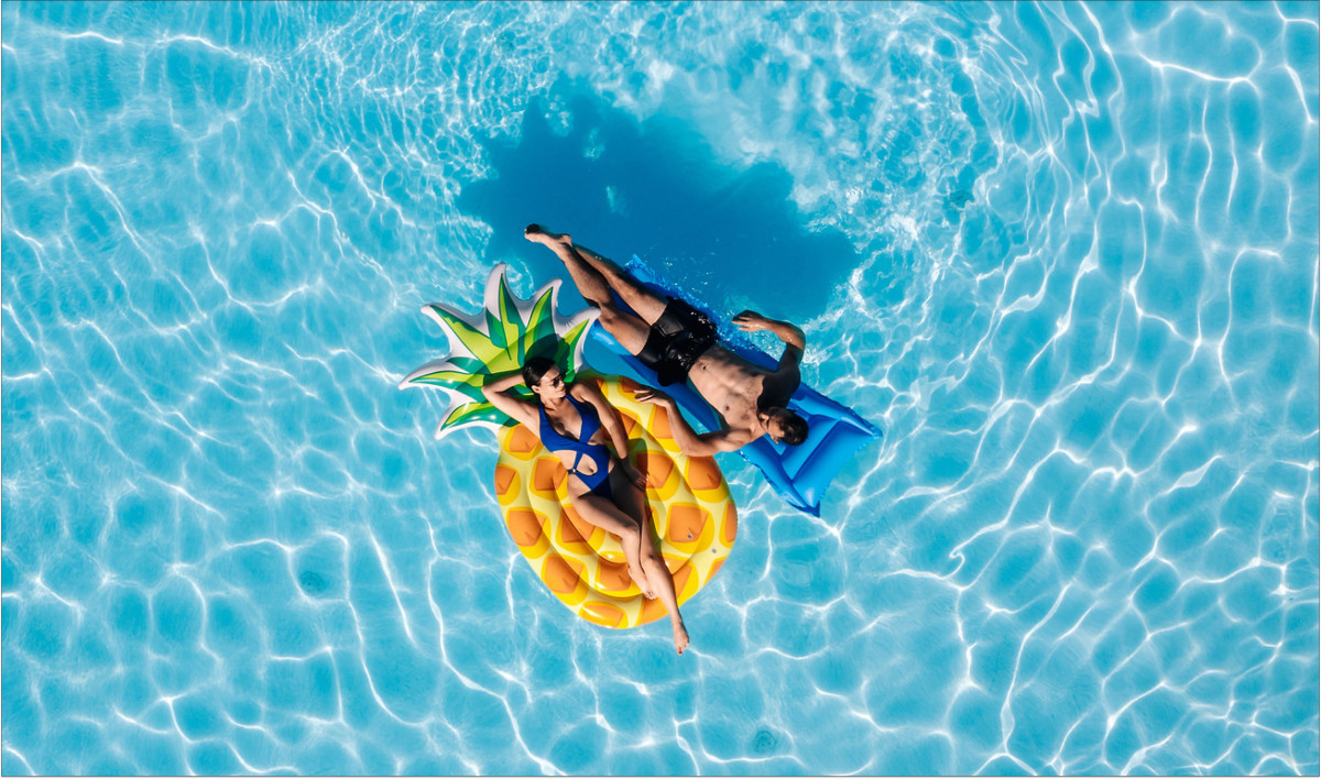 Ein Paar badet auf Luftmatratzen in einem Pool