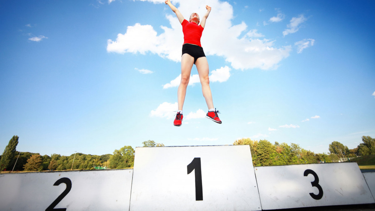 Springende Frau auf Siegertreppe