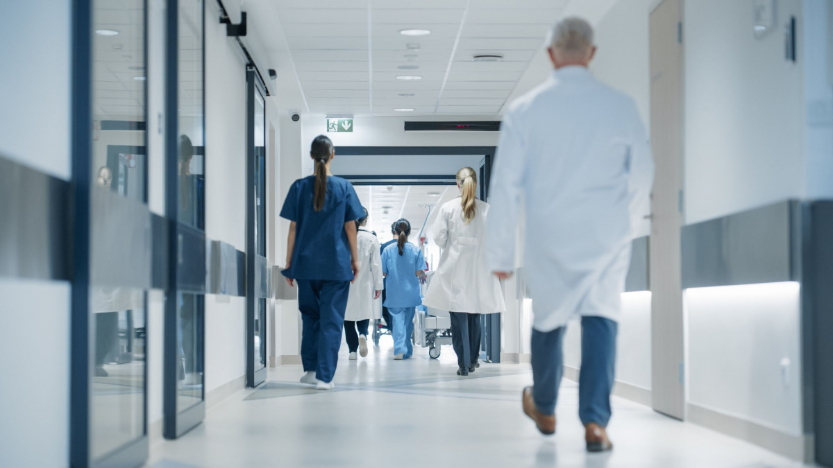 Blick in einen Gang in einem Krankenhaus, in dem Ärzte und Schwestern unterwegs sind