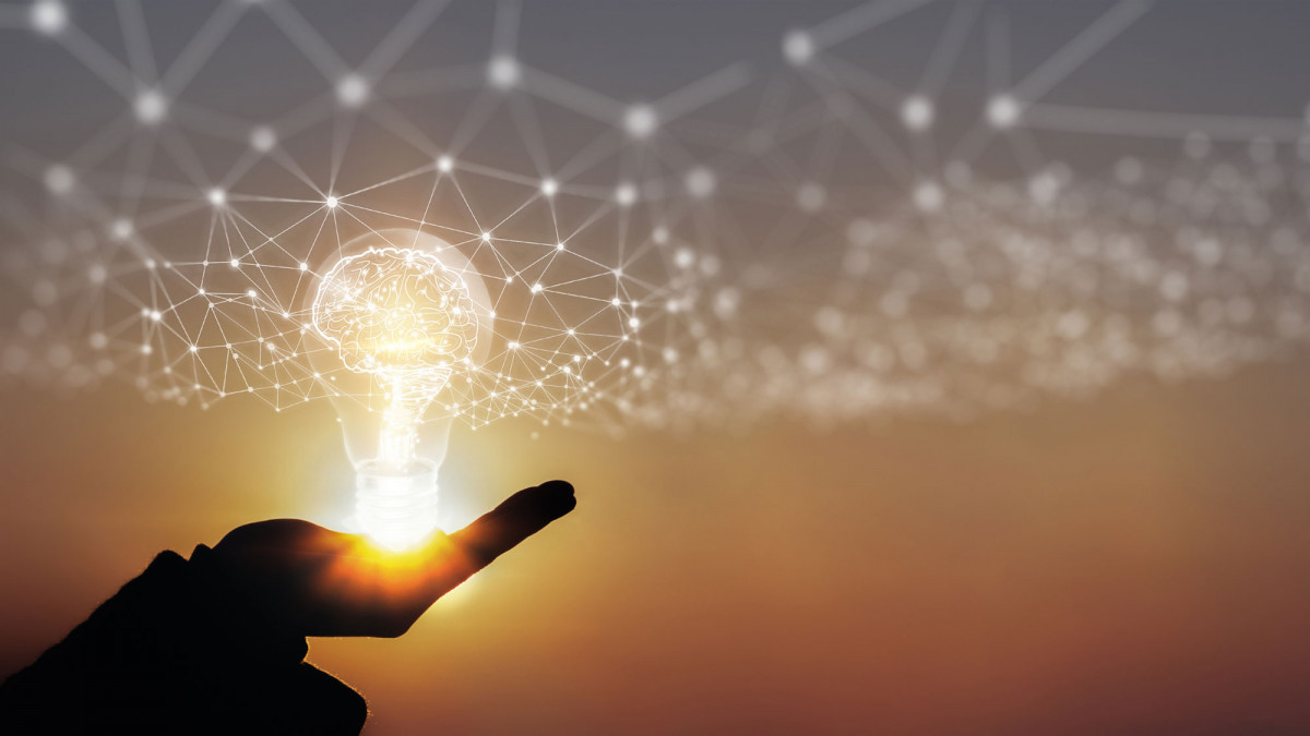 Hand hält leuchtende Glühbirne