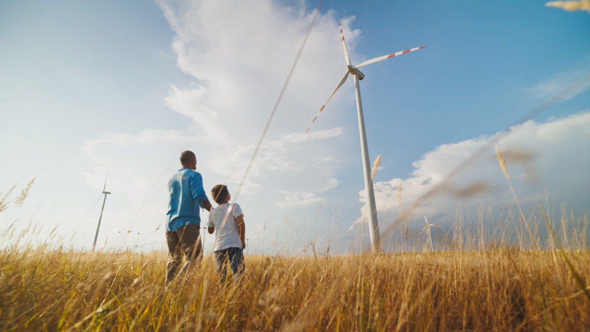 Vater mit Sohn betrachten eine Windkraftanlage