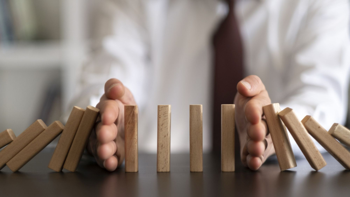 Hände halten umstürzende Holzbausteine auf.