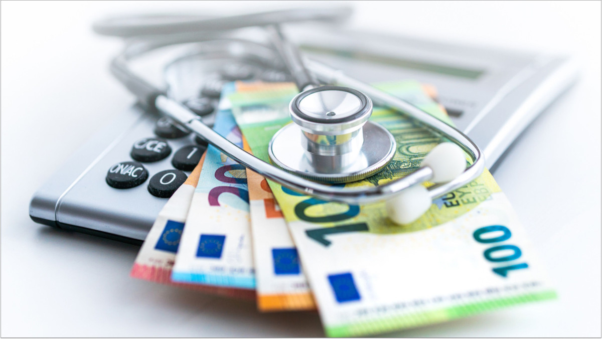 Ein Stethoskop liegt auf mehreren Geldscheinen und einem Taschenrechner